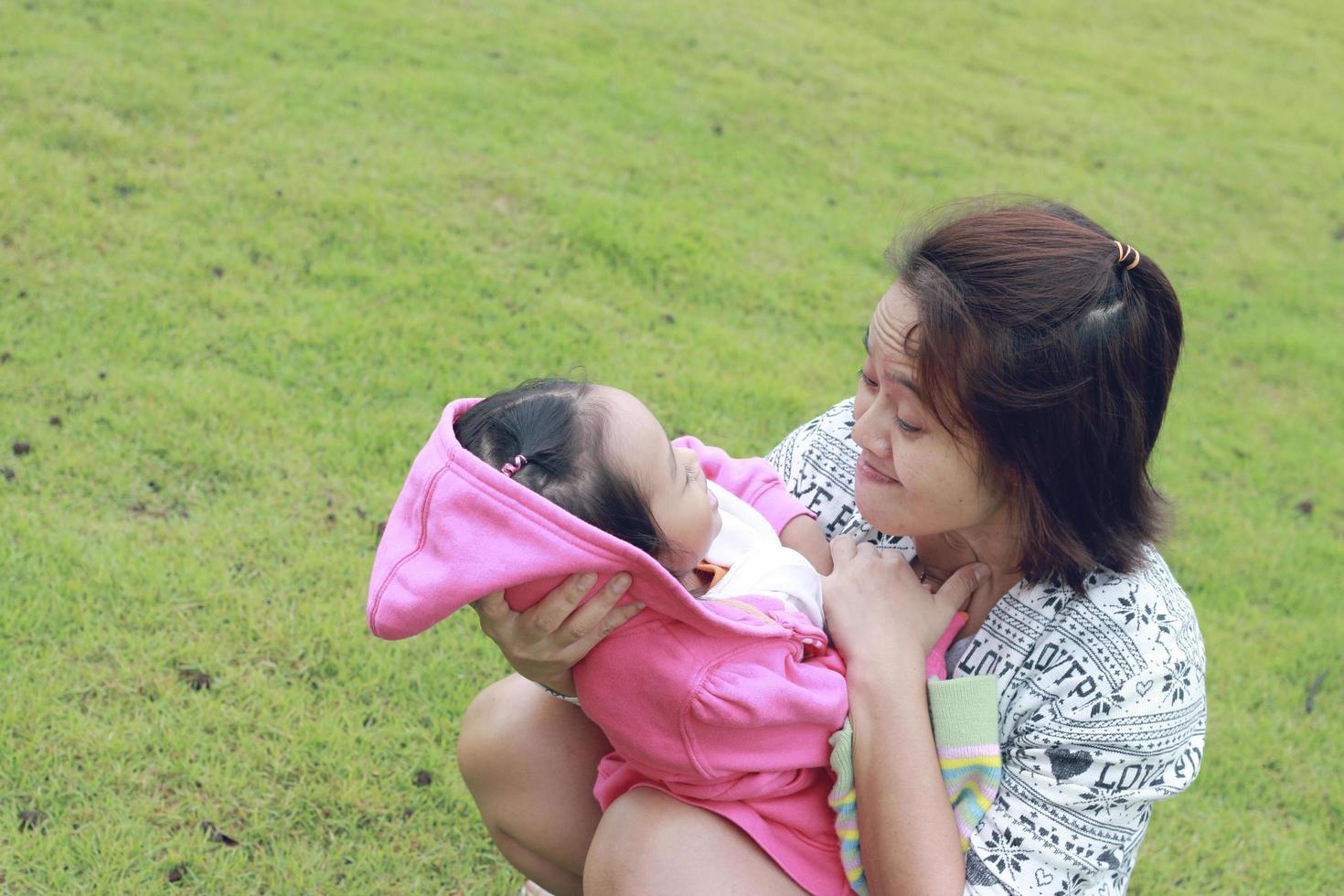 Mother and daughter happily play on the green lawn photo