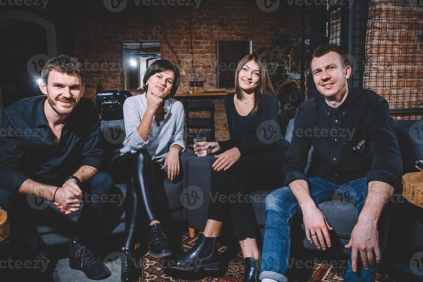 Cheerful guys and girls are sitting on the couch and smiling looking into the camera photo