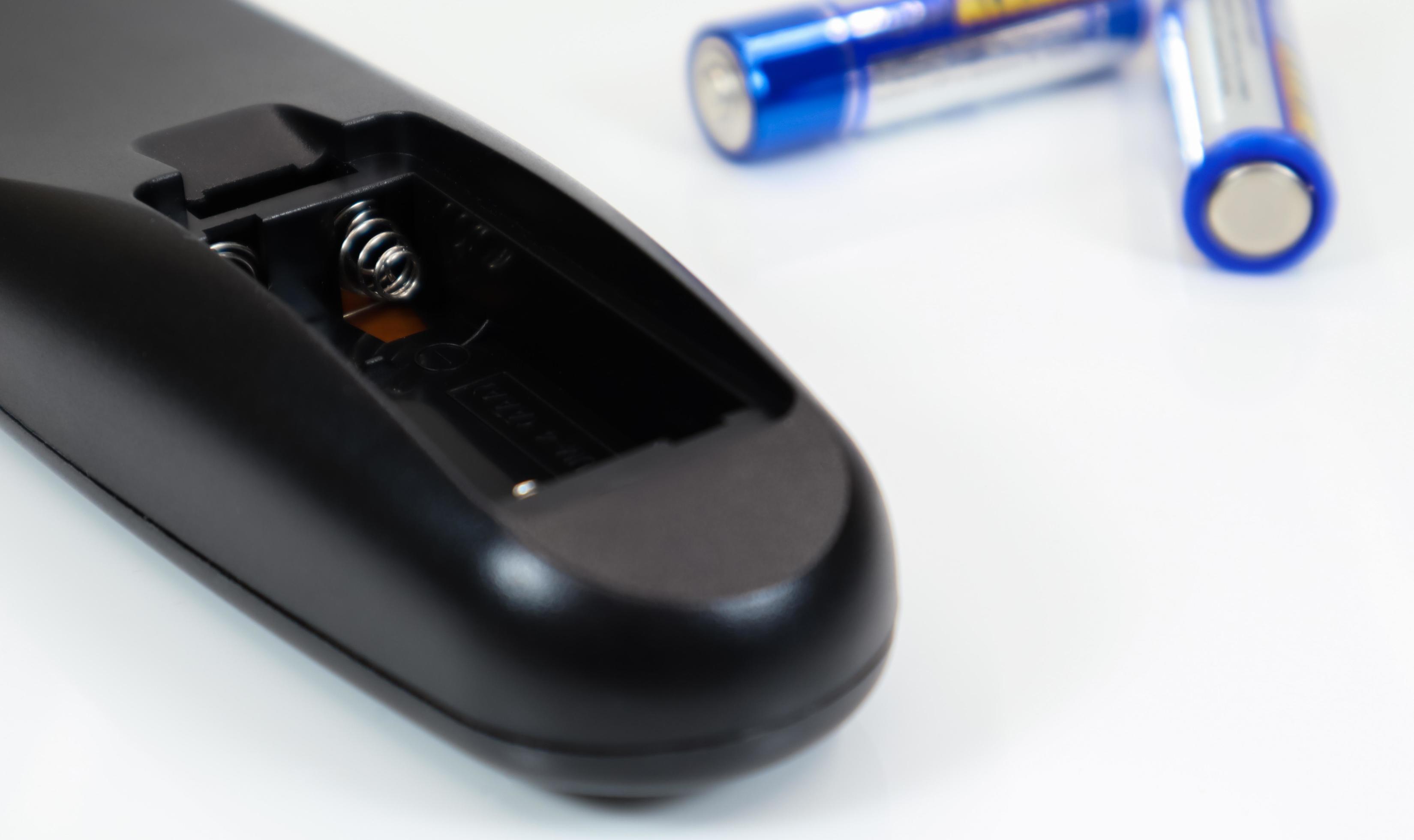 Black remote control with blue AAA batteries on a white background