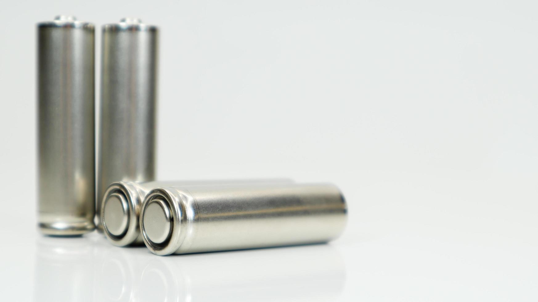 AA alkaline rechargeable batteries on white glossy background with reflection. Close up four empty batteries with copy space. photo