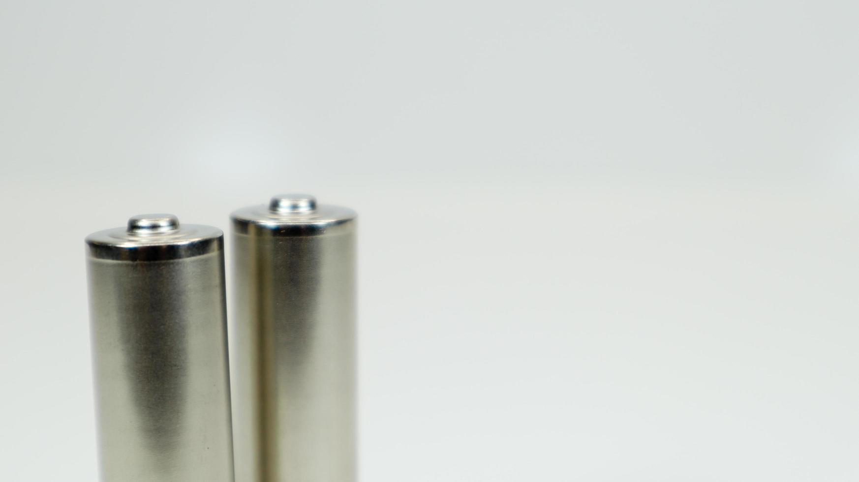 AA alkaline rechargeable batteries on white glossy background with reflection. Close up two empty batteries with copy space. photo