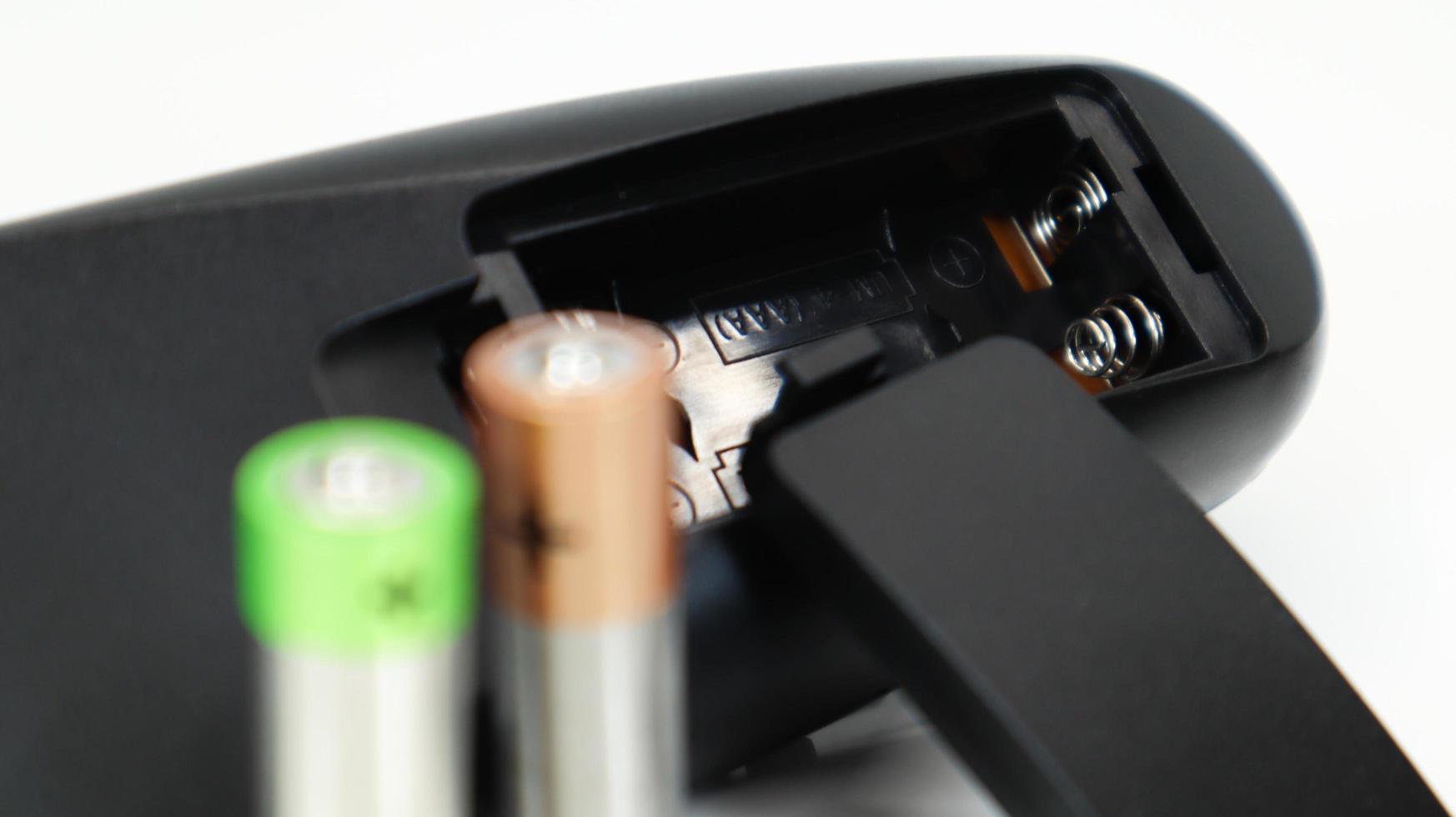 Black TV remote control with AAA alkaline batteries on a white background. Battery replacement, spare parts. Close up of an empty battery compartment of the remote control. photo