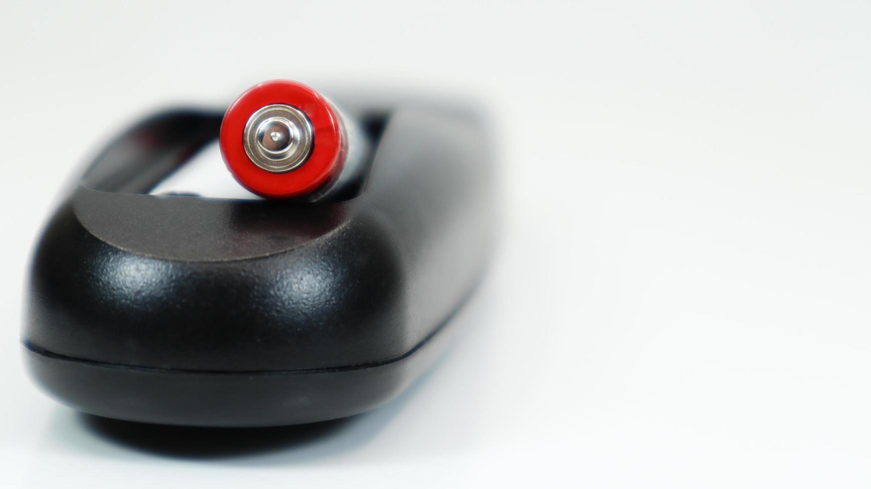 Black TV remote control with AAA alkaline batteries on a white background. Battery replacement, spare parts. Close up of the battery compartment of the remote control. photo
