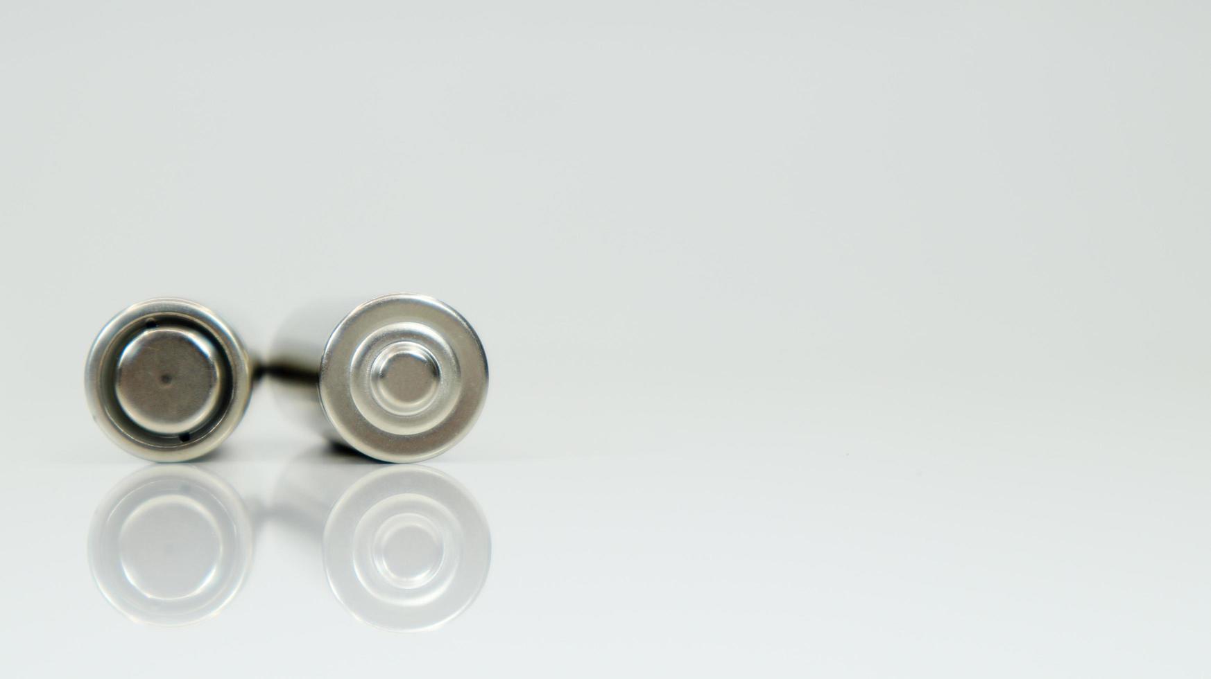 AA alkaline rechargeable batteries on white glossy background with reflection. Close up two empty batteries with copy space. photo