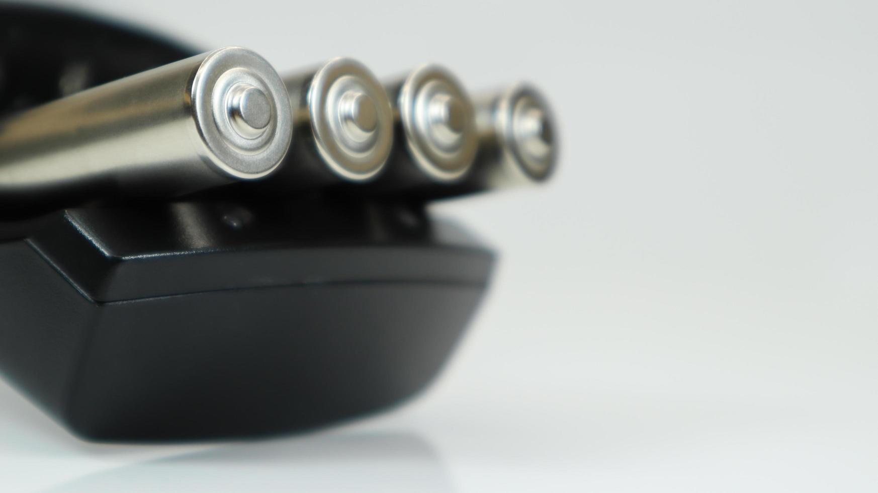Rechargeable alkaline batteries in a battery charger on a white background. AA fast charger in black. The battery is charging. photo
