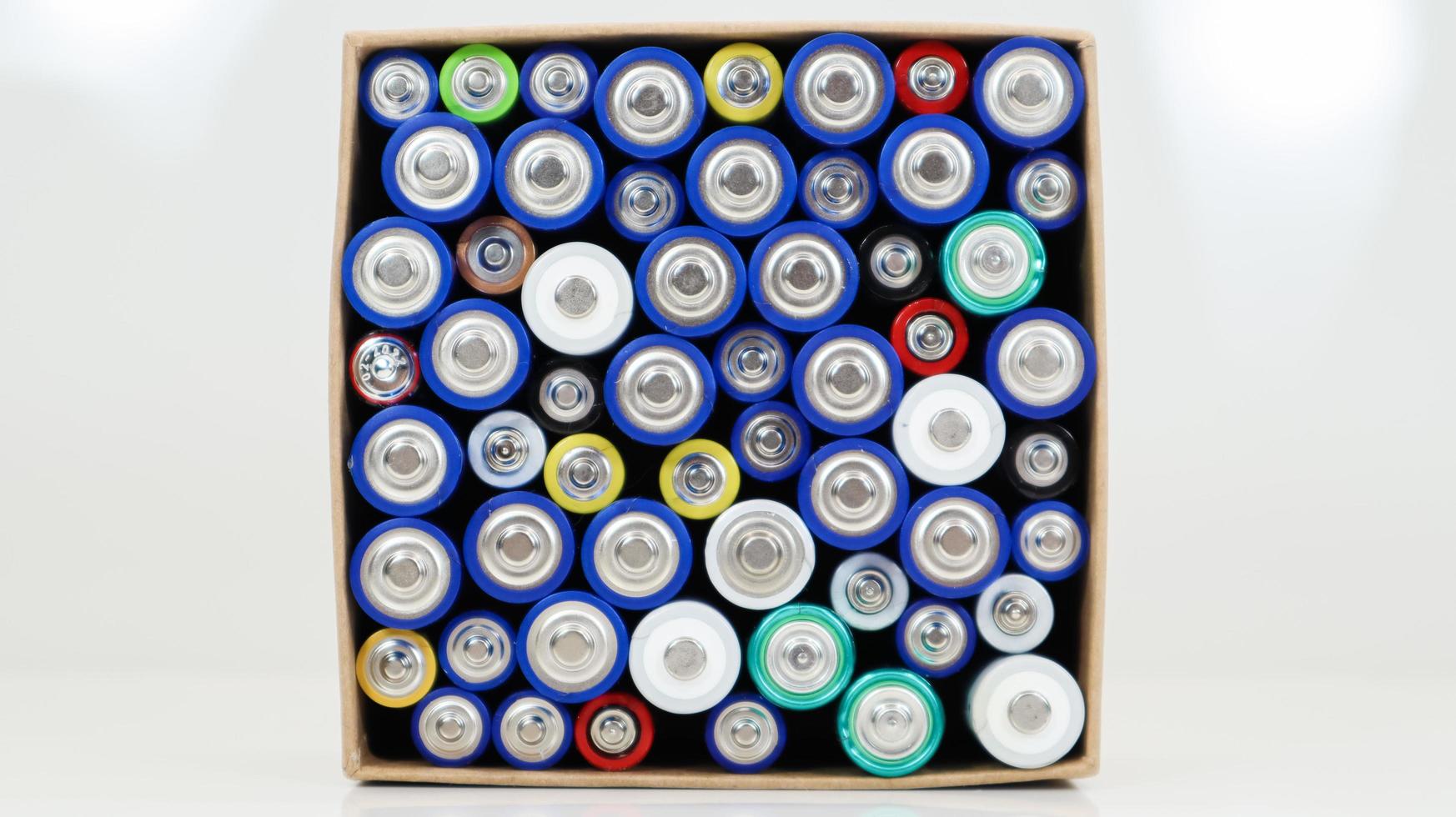 vista superior del fondo de pilas aaa aa y pilas recargables. elección de baterías. concepto de suministro y reciclaje de energía. texturas de elementos eléctricos empaquetados juntos en una caja. foto