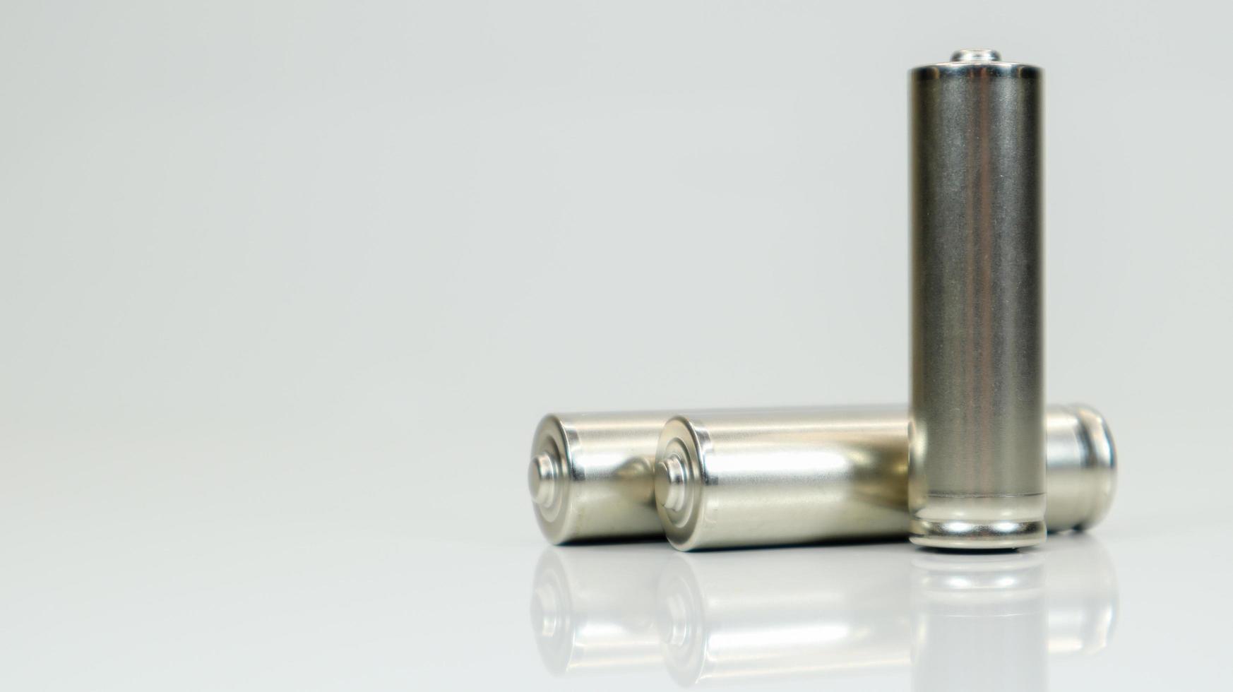 AA alkaline rechargeable batteries on white glossy background with reflection. Close up three empty batteries with copy space. photo