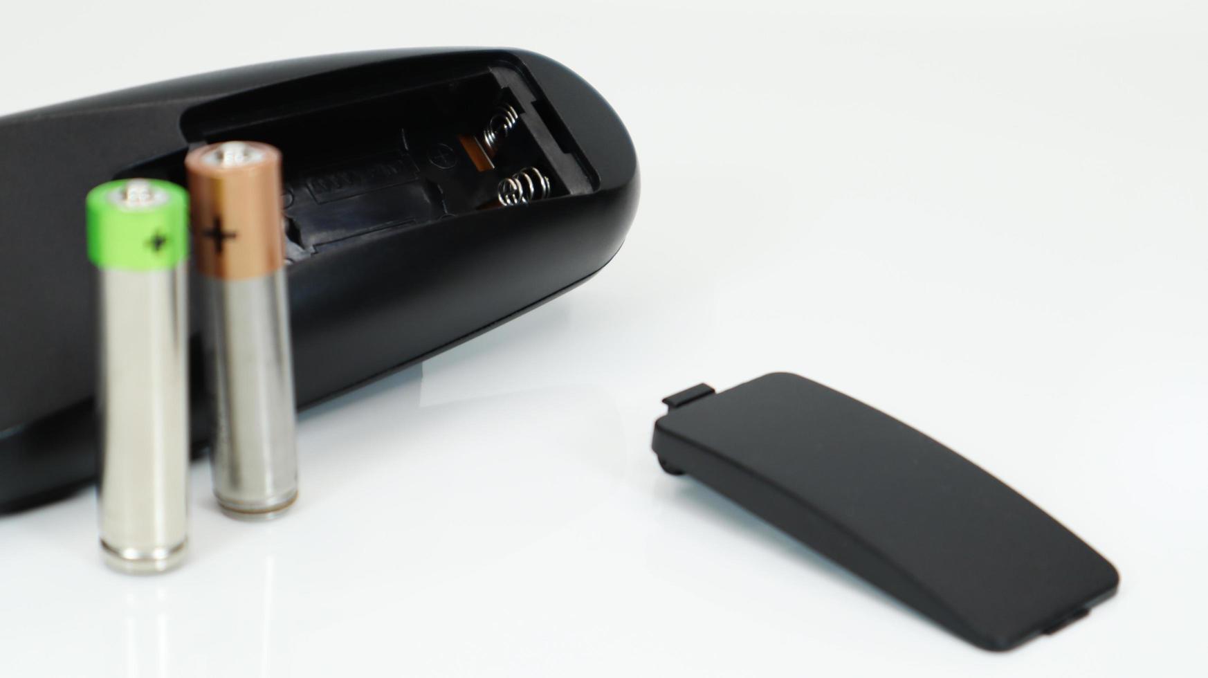 Black TV remote control with AAA alkaline batteries on a white background. Battery replacement, spare parts. Close up of an empty battery compartment of the remote control. photo