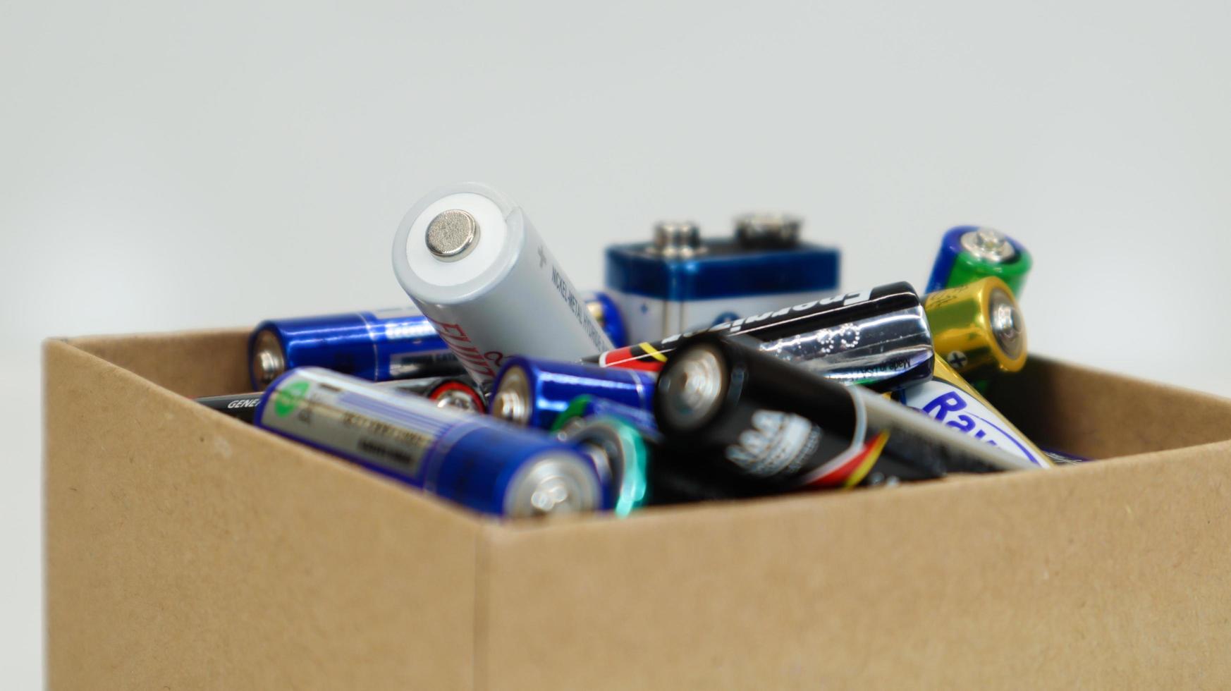 A cardboard box on a white background full of used household AA, AAA, PP3 alkaline batteries collected for recycling. Recycling and ecology problems. Ukraine, Kiev - January 7, 2021. photo