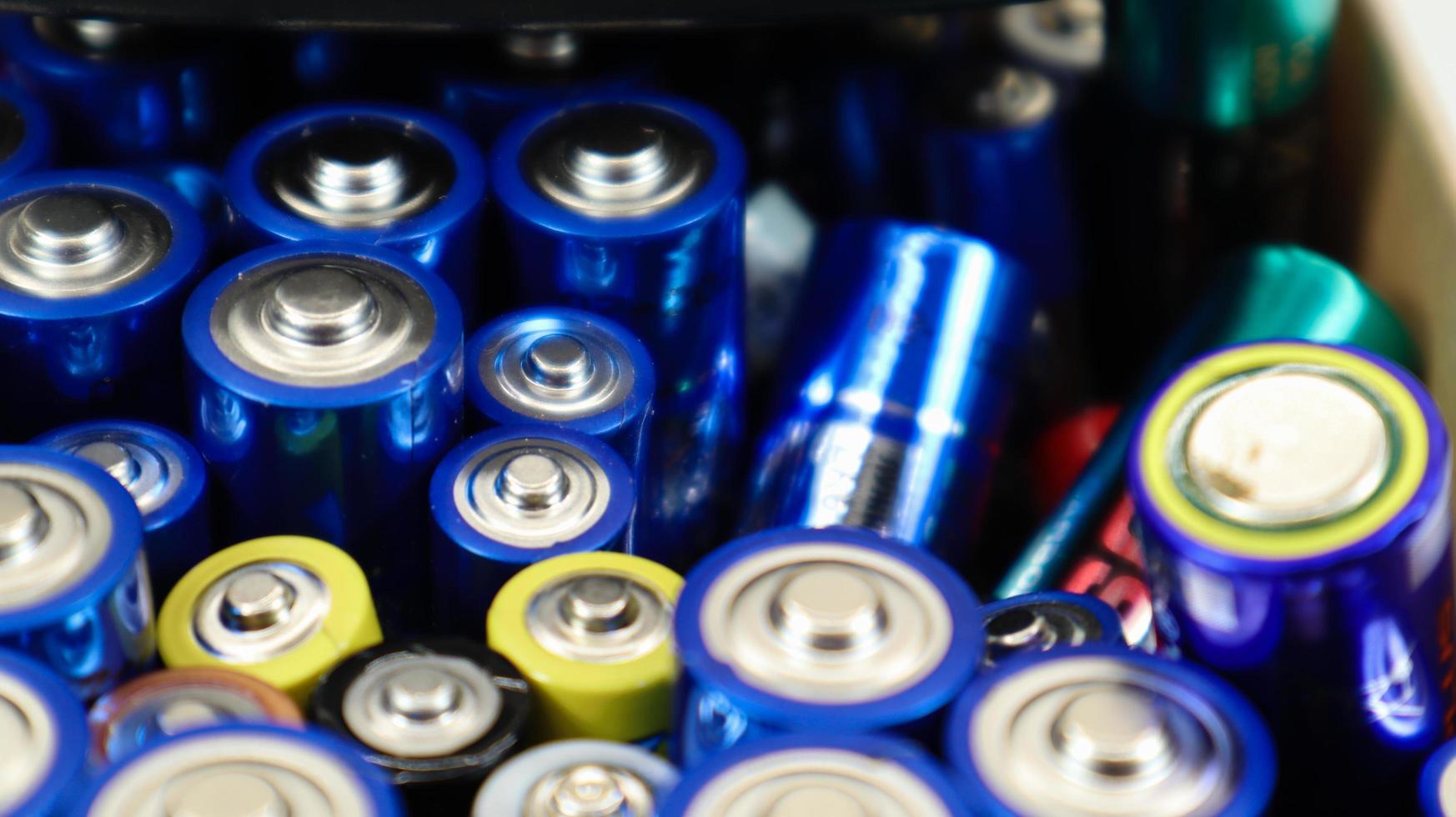 A cardboard box on a white background full of used household AA, AAA alkaline batteries collected for recycling. Recycling and ecology problems. photo