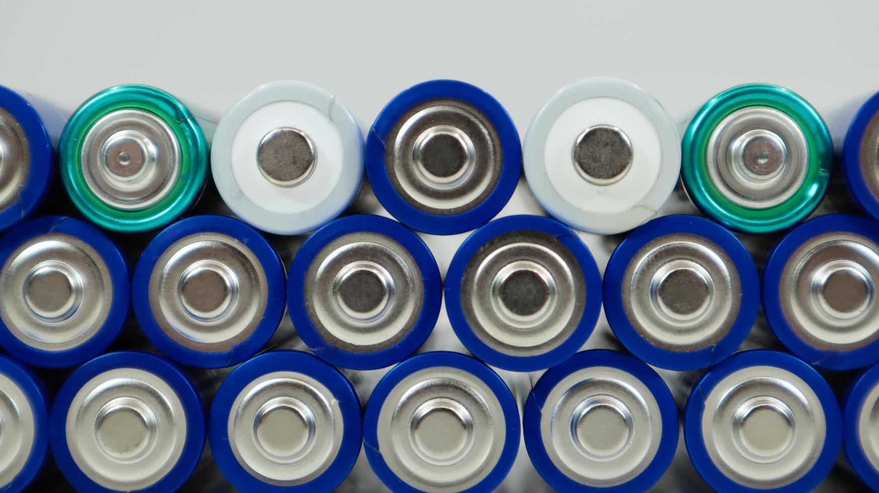Lots of AA and AAA alkaline batteries on a white background. Ecological recycling concept. The terminals of the disposable batteries are close together and form a beautiful backdrop. Energy source. photo
