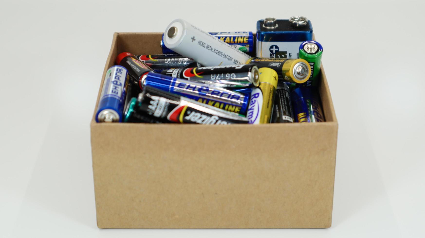 A cardboard box on a white background full of used household AA, AAA, PP3 alkaline batteries collected for recycling. Recycling and ecology problems. Ukraine, Kiev - January 7, 2021. photo