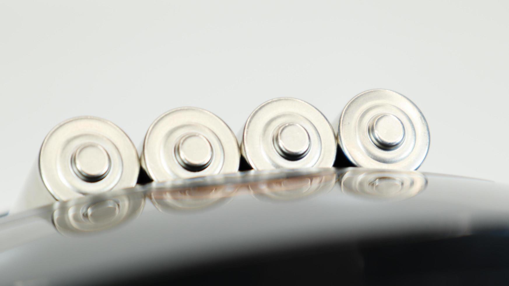 Rechargeable alkaline batteries in a battery charger on a white background. AA fast charger in black. The battery is charging. photo