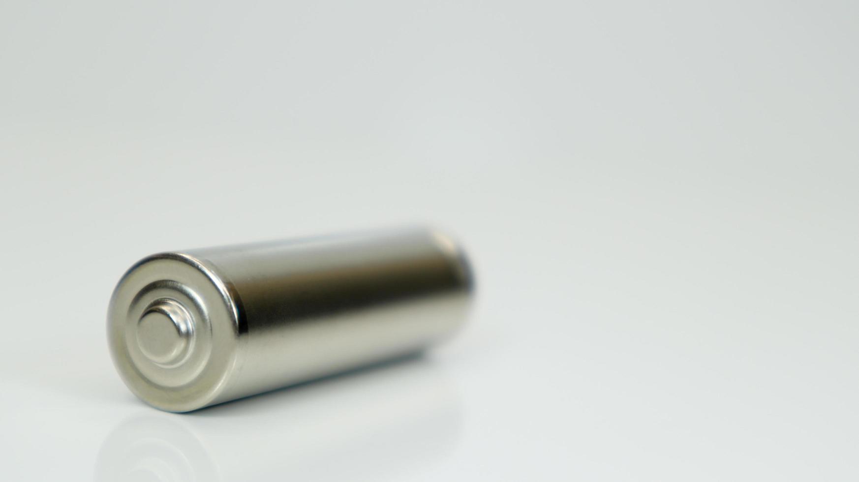 AA alkaline rechargeable battery on white glossy background with reflection. Close one empty battery with copy space. photo