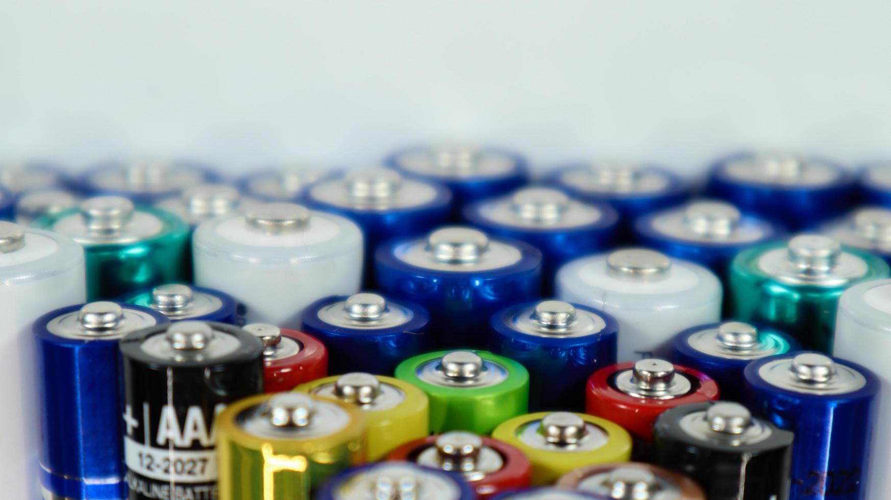 Lots of AA and AAA alkaline batteries on a white background. Ecological recycling concept. The terminals of the disposable batteries are close together and form a beautiful backdrop. Energy source. photo