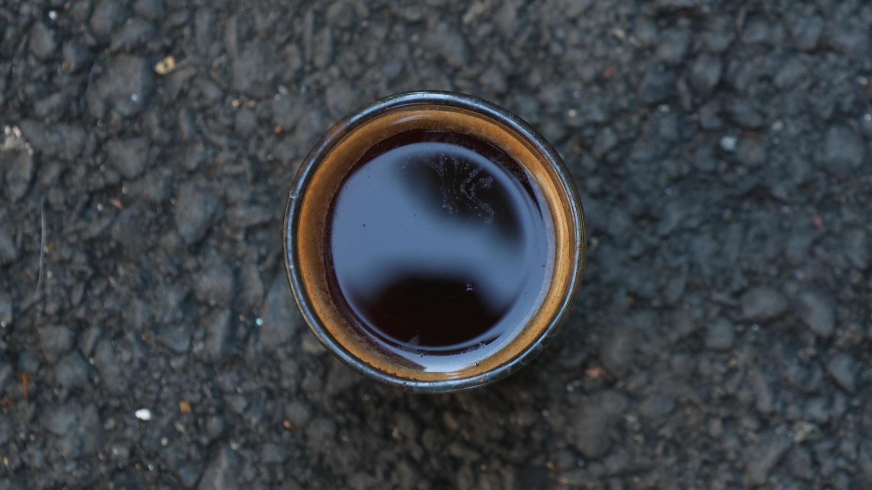 black coffee in a cup placed on asphalt photo