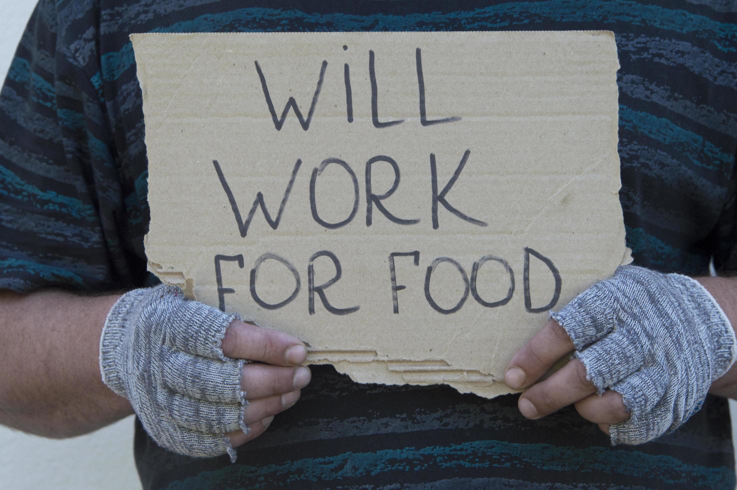 The hands of a homeless person hold a sign with the inscription. Poverty, unemployment. photo