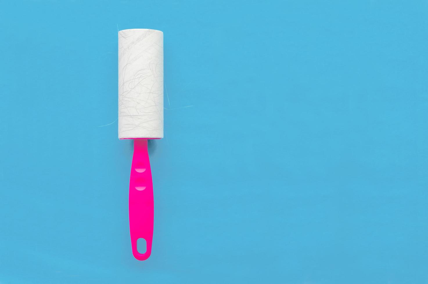 Glue roller for cleaning clothes from wool and animal hair on a blue background with a place for writing. photo