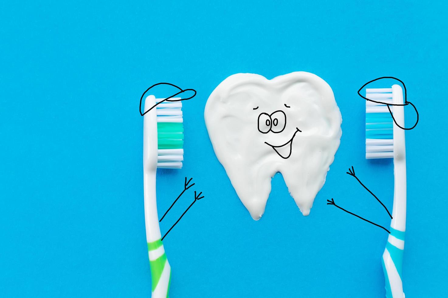 Multi-colored toothbrushes on a blue background with a tooth pattern drawn with toothpaste in the form of cartoon characters. The view from the top.The concept of dental health. photo