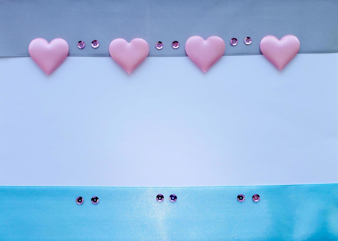 Template. Satin ribbons in blue and gray with pink hearts and sequins on a white background with a place for the inscription. photo