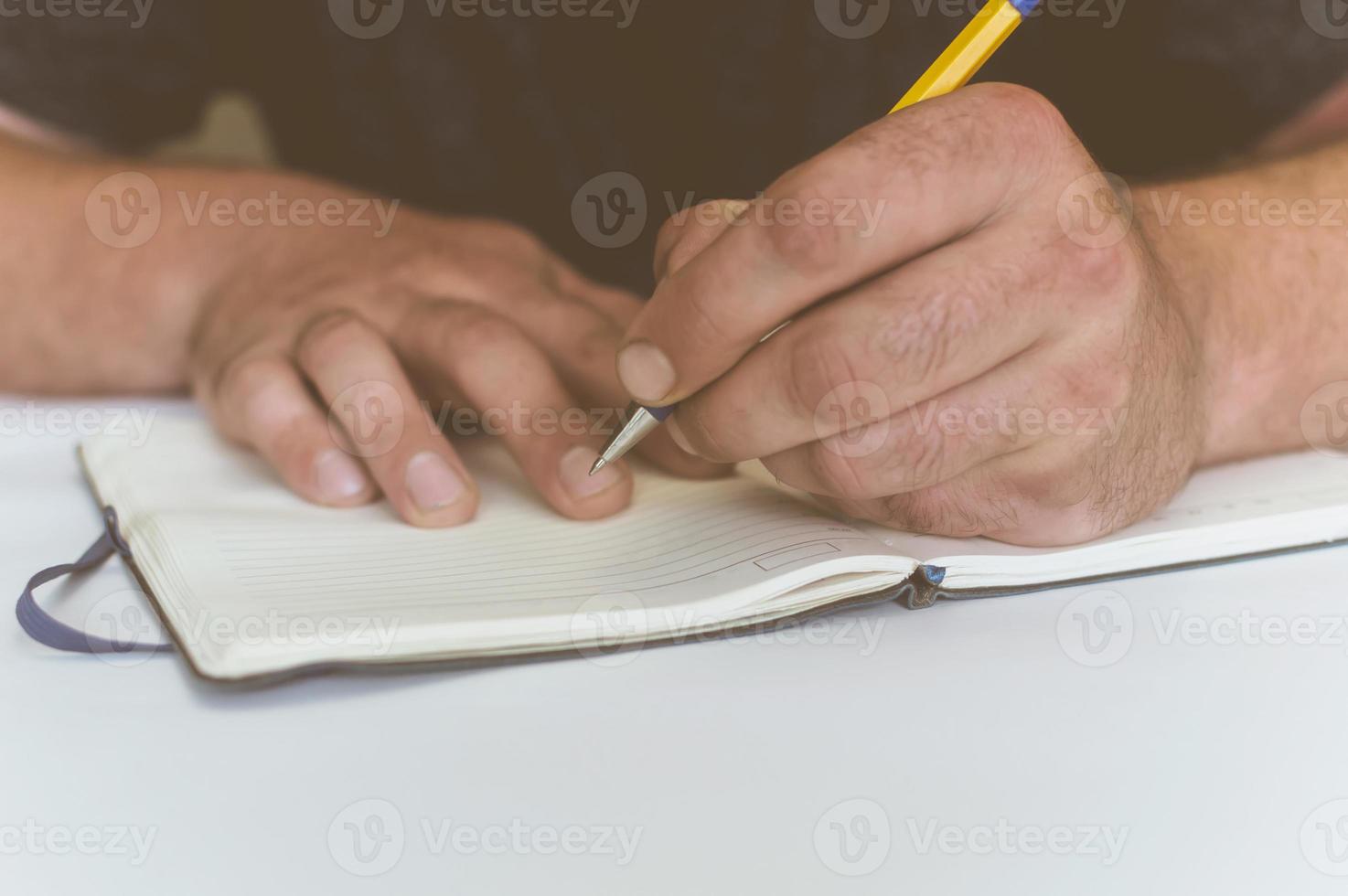 una persona hace una entrada en un cuaderno para hacer negocios foto