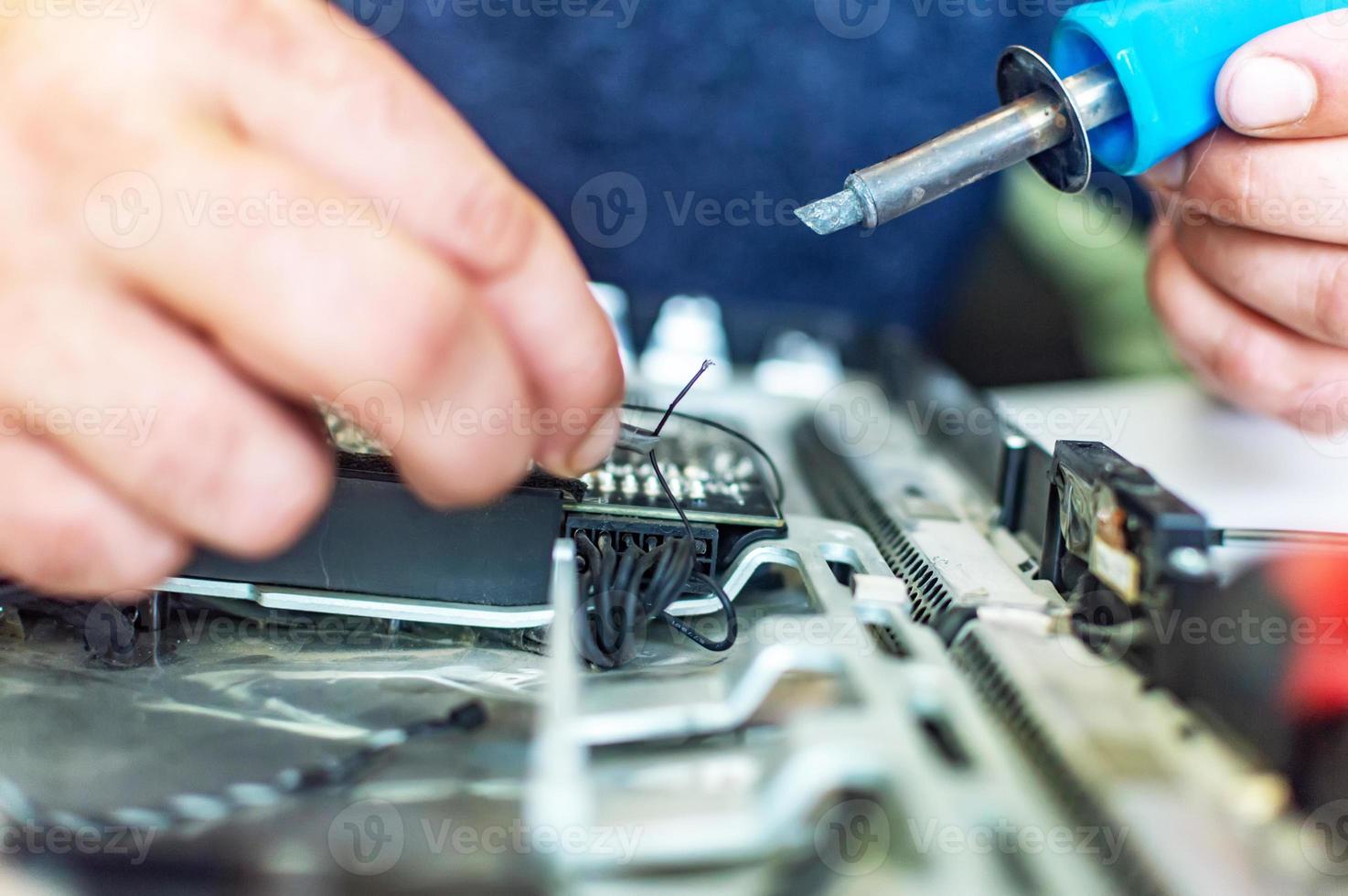 un hombre repara una computadora, suelda una placa, repara electrónica y tecnologías modernas foto