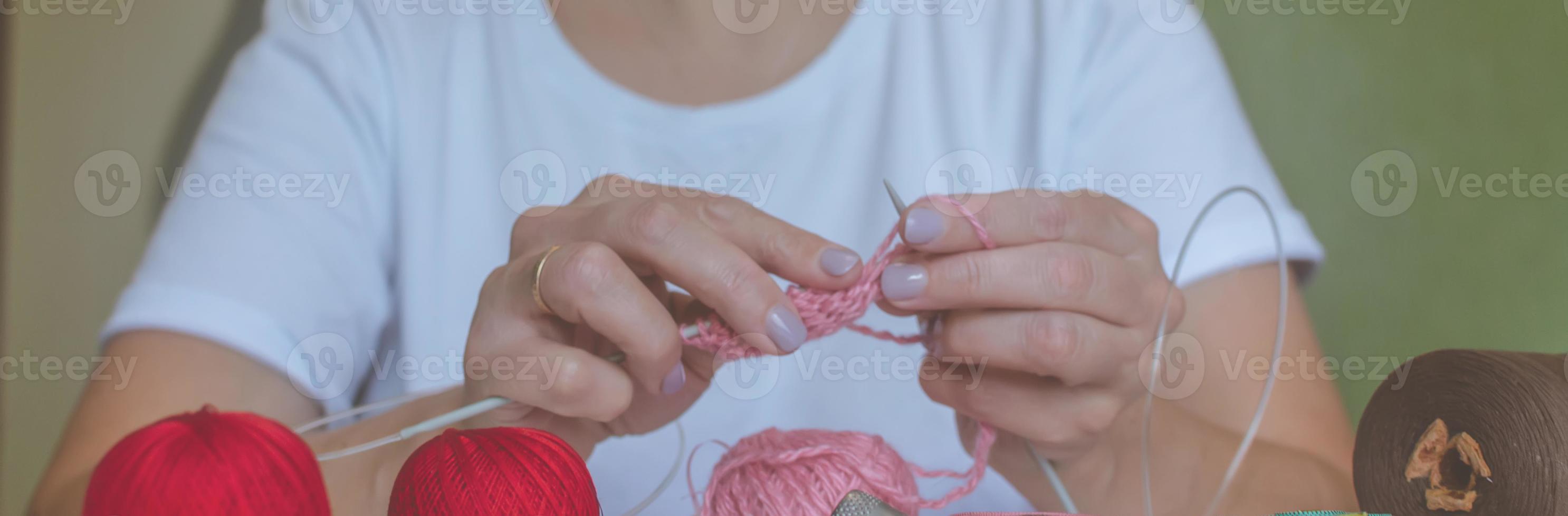 girl knits yarn with knitting needles and crochet at home. in a white t-shirt. hand knits photo