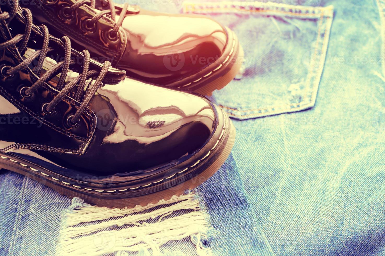 Black patent leather boots on ragged jisas close-up. The concept of travel. photo