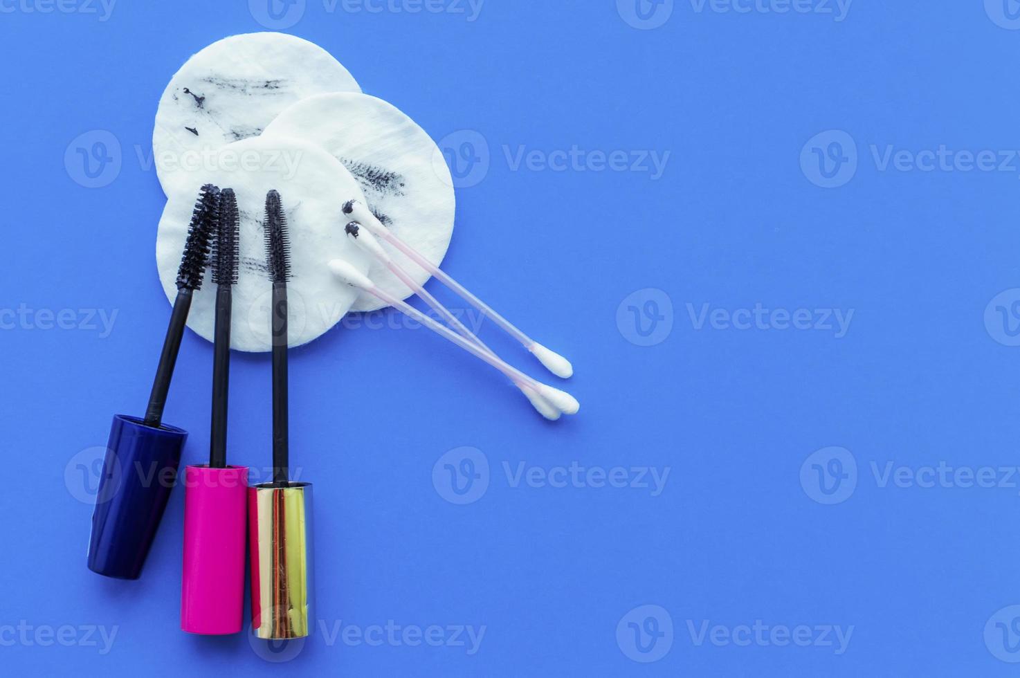 Use dirty cotton pads, mascara brushes, and cotton swabs after removing makeup on a blue background with space for writing photo