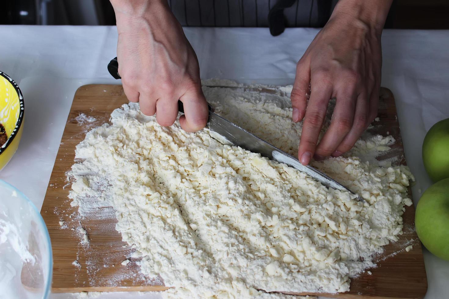 The cook's hands chop butter and flour on a wooden Board with a knife. Homemade cake. Housework. photo