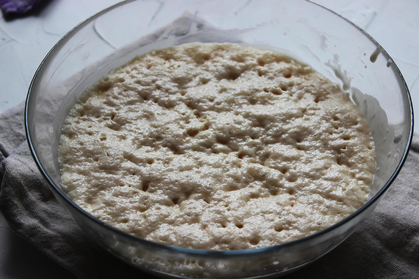Yeast dough in a large glass bowl. Homemade cake. Concept of homework during the quarantine period. photo