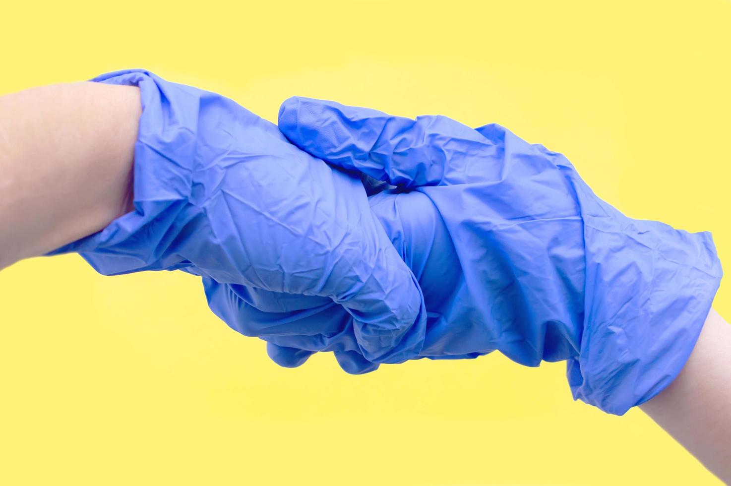 Hands of two people in blue sterile gloves say Hello. The concept of protection from viruses. Selective focus. photo