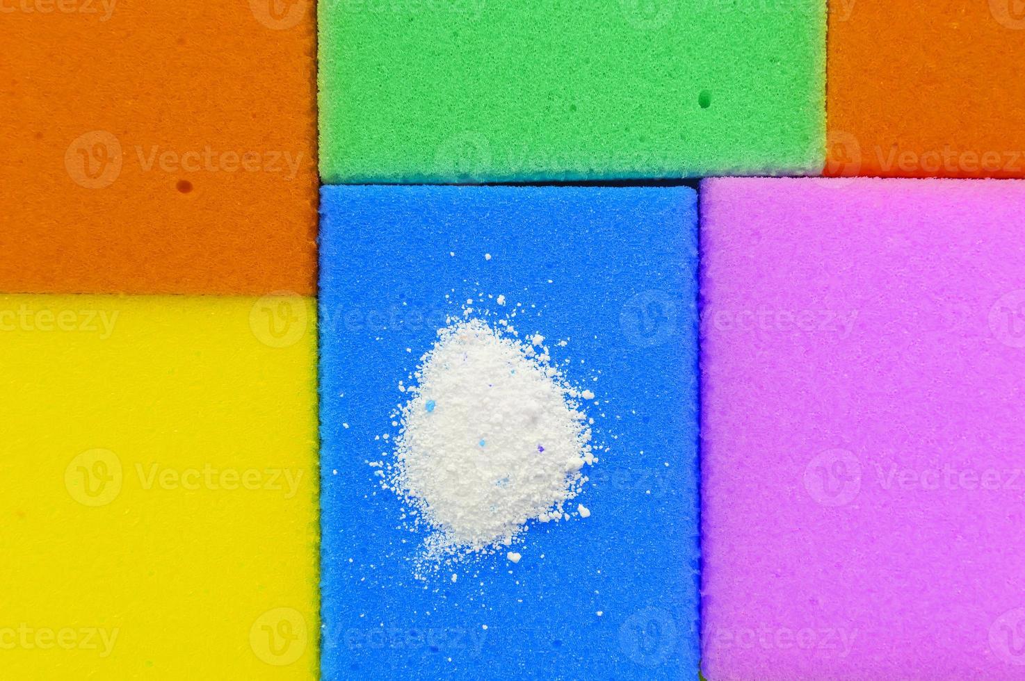 Cleaning powder on a red dishwashing sponge next to multi-colored sponges.The concept of homework. photo