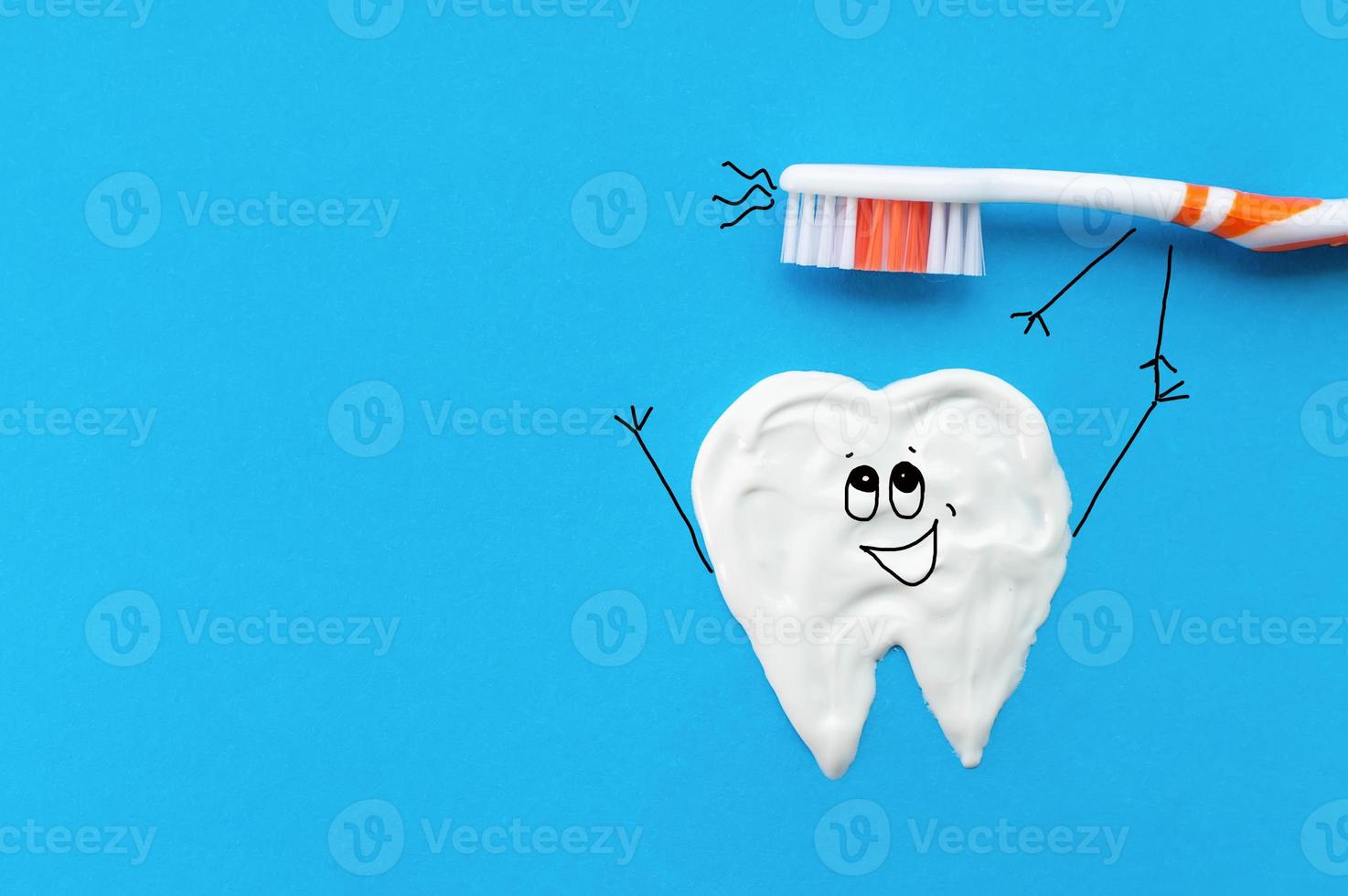 Orange toothbrush in the form of a cartoon character on a blue background with a tooth pattern drawn with toothpaste pulling their hands together.The concept of dental health. photo