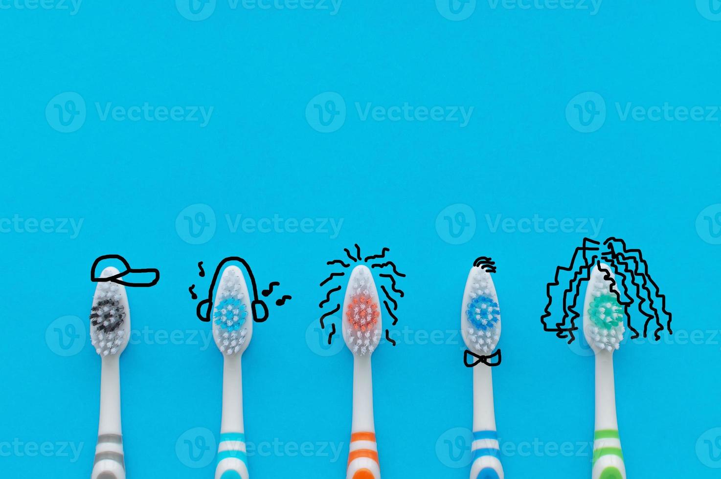 Colorful toothbrushes on a blue background in the form of cartoon characters. The view from the top. Close up. Concept of family hygiene. photo