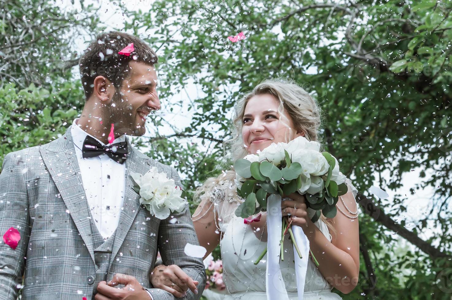 bride and groom at the wedding ceremony. congratulations of the guests. showering with rose petals. selective focus. film grain. photo