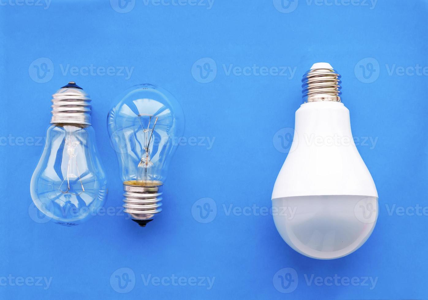 Energy-saving lamp with incandescent lamps in a row on a blue background. The concept of saving energy. photo
