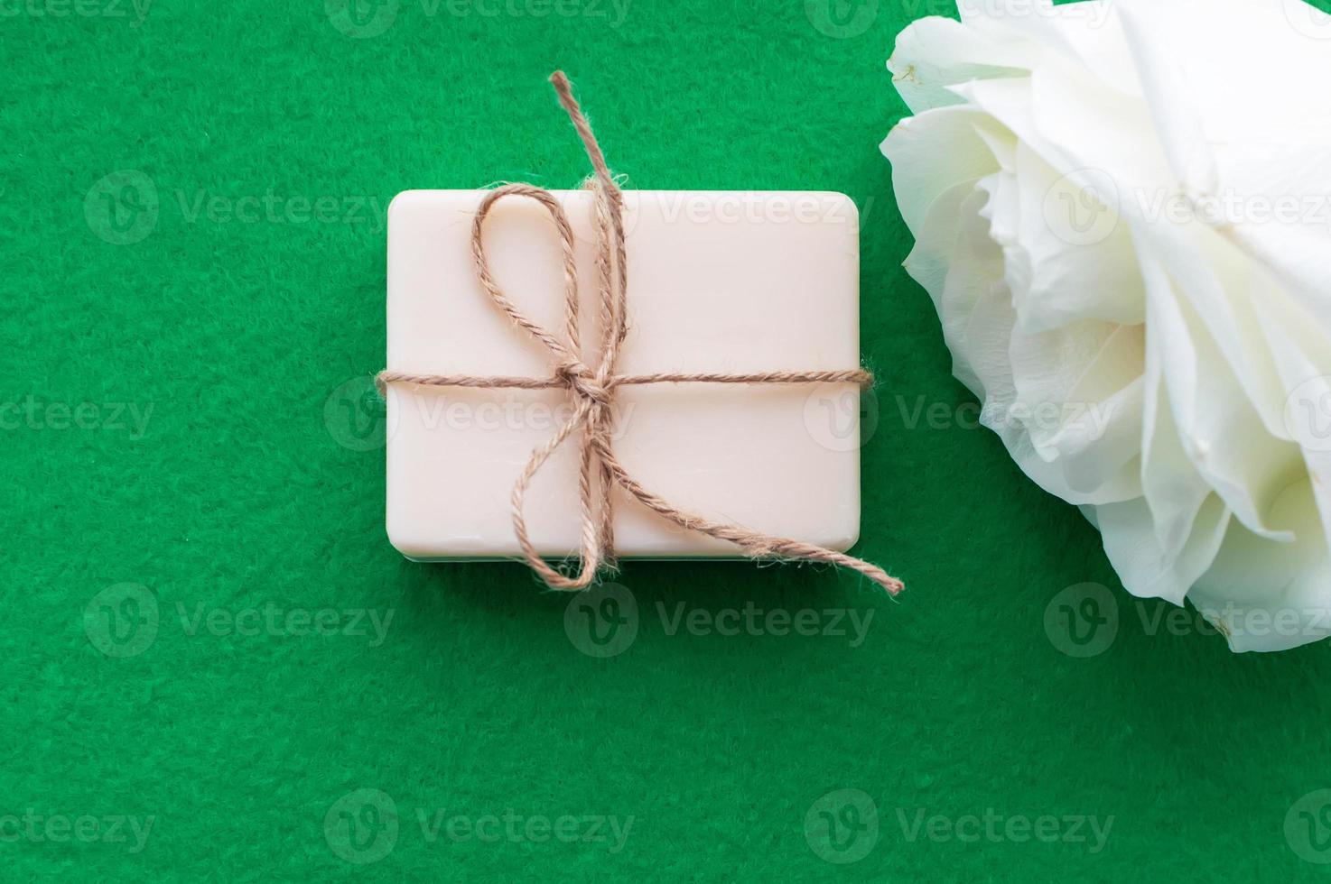 the soap is tied with a rope and a white rose on a green background with a place for the inscription. Concept of hygiene and Spa procedures. photo
