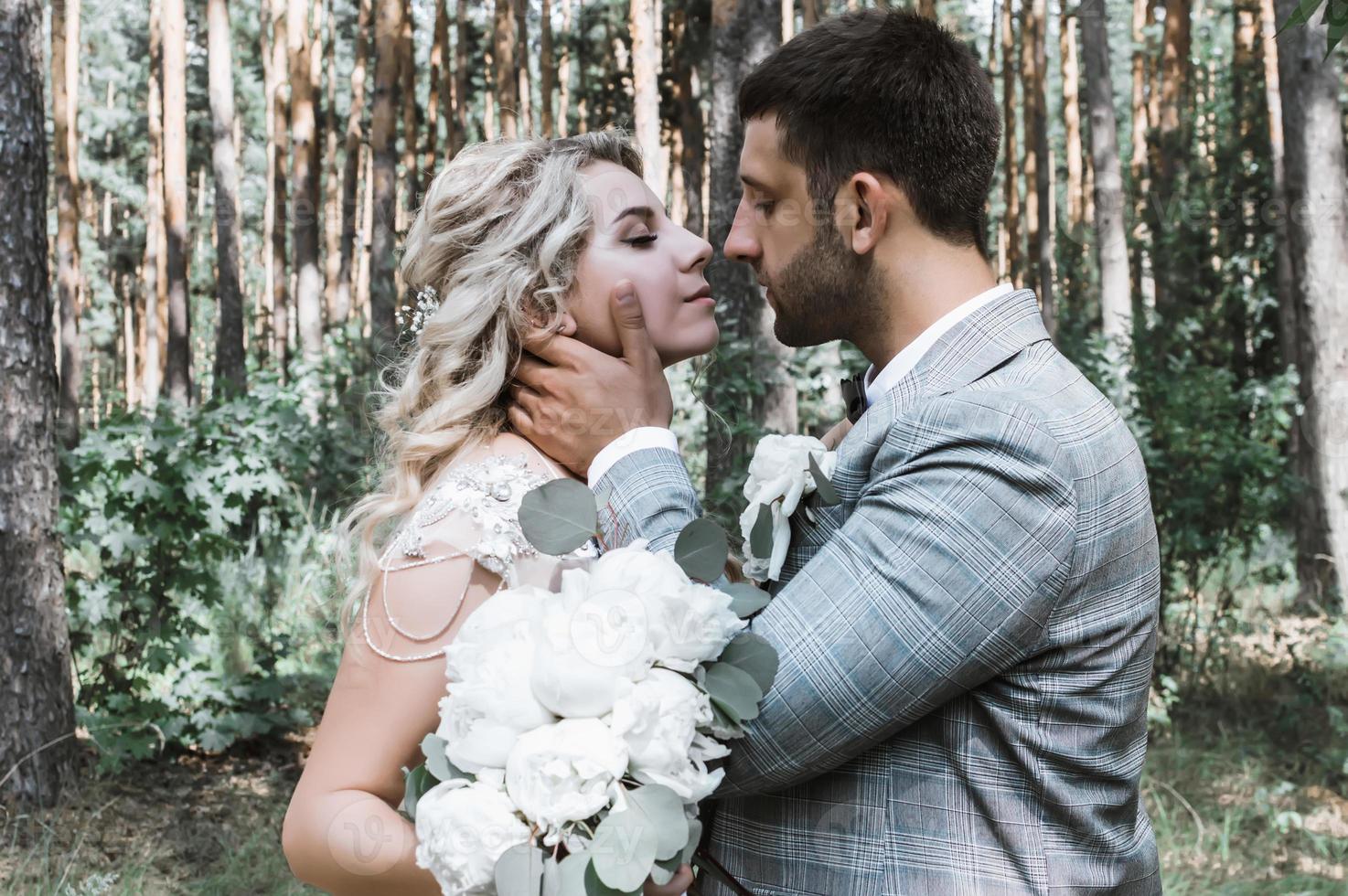 the bride and groom kiss in the forest at the wedding ceremony. selective focus. film grain. photo