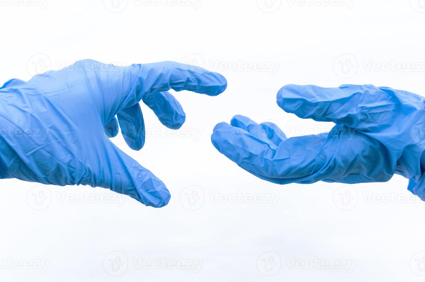 Hands of two people in blue sterile gloves greet on a white background. The concept of virus protection. Selective focus. photo
