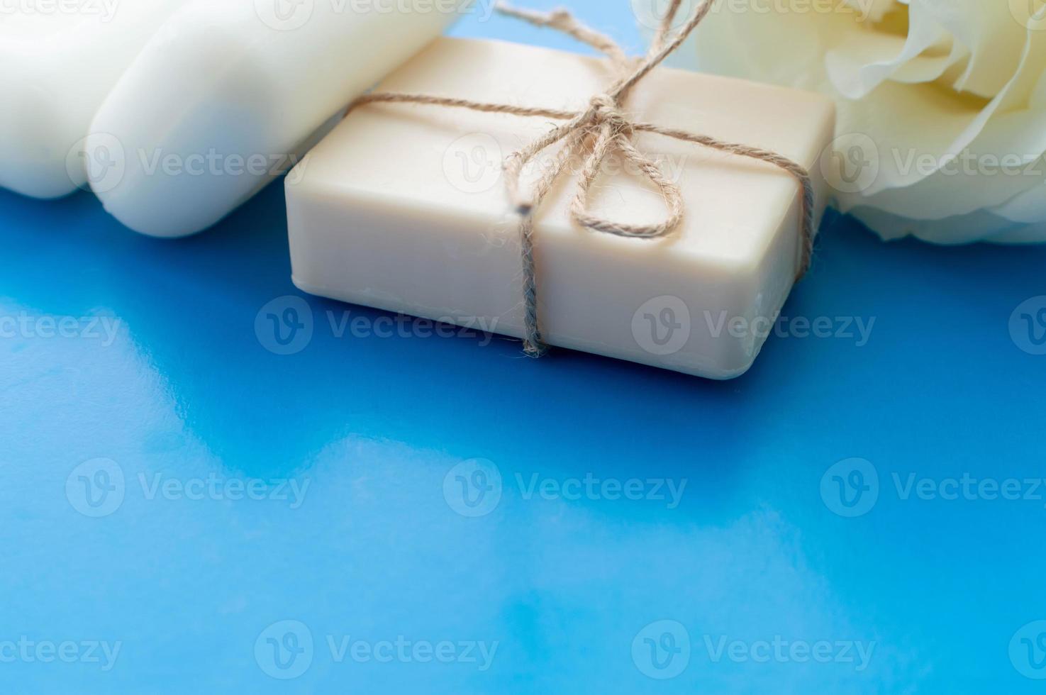 the soap is tied with a rope and a white rose on a blue background with a place for the inscription. Concept of hygiene and Spa procedures. photo