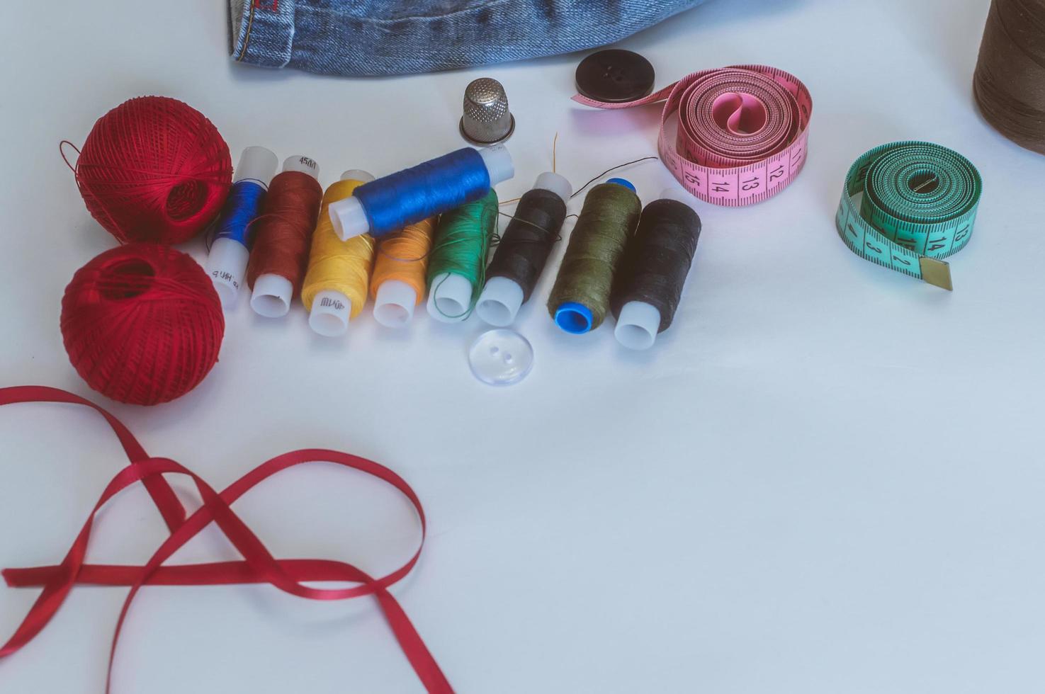 women's hands, a tailor sews clothes at a table on which spools of thread lie photo