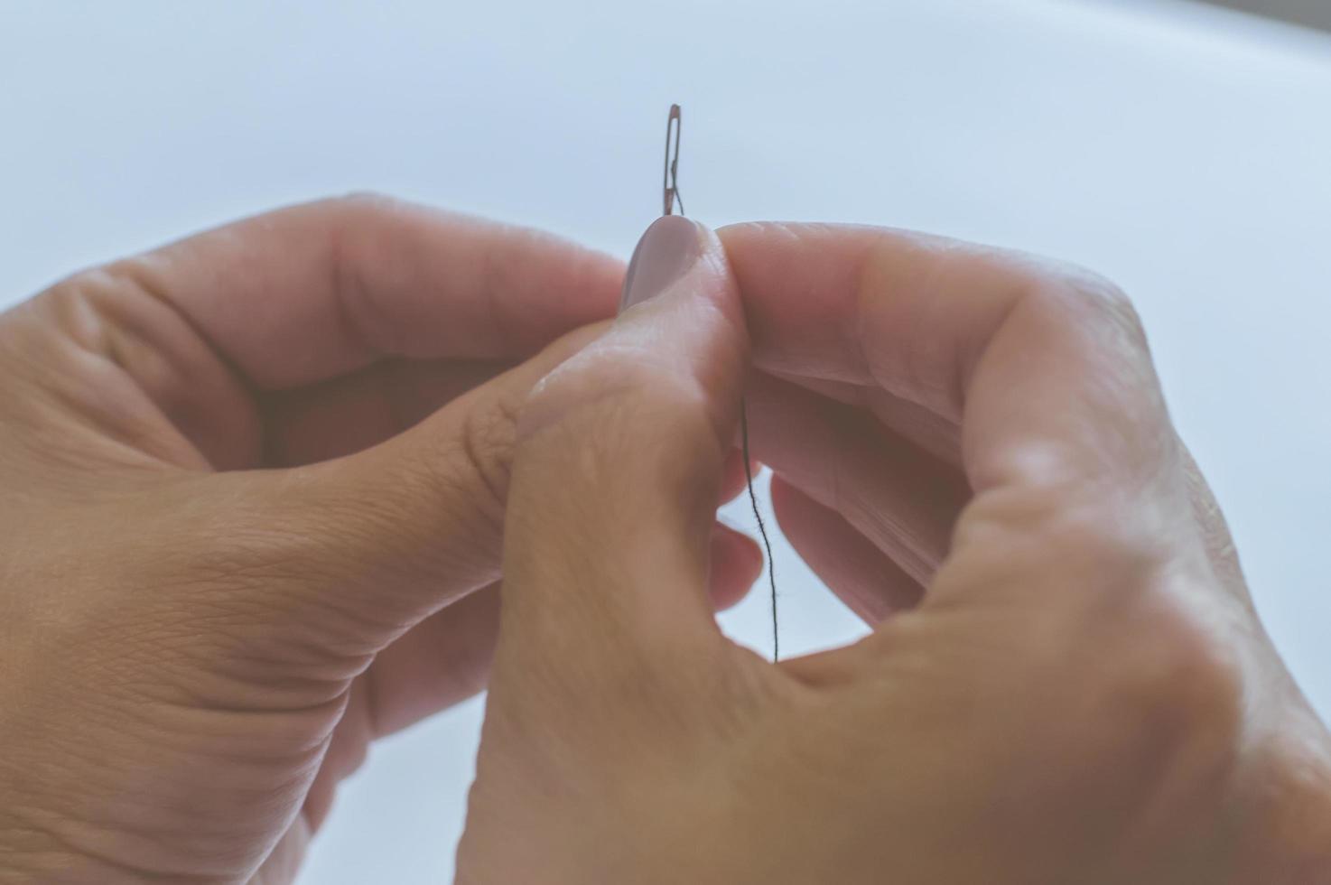 women's hands, a tailor sews clothes at a table on which spools of thread lie photo