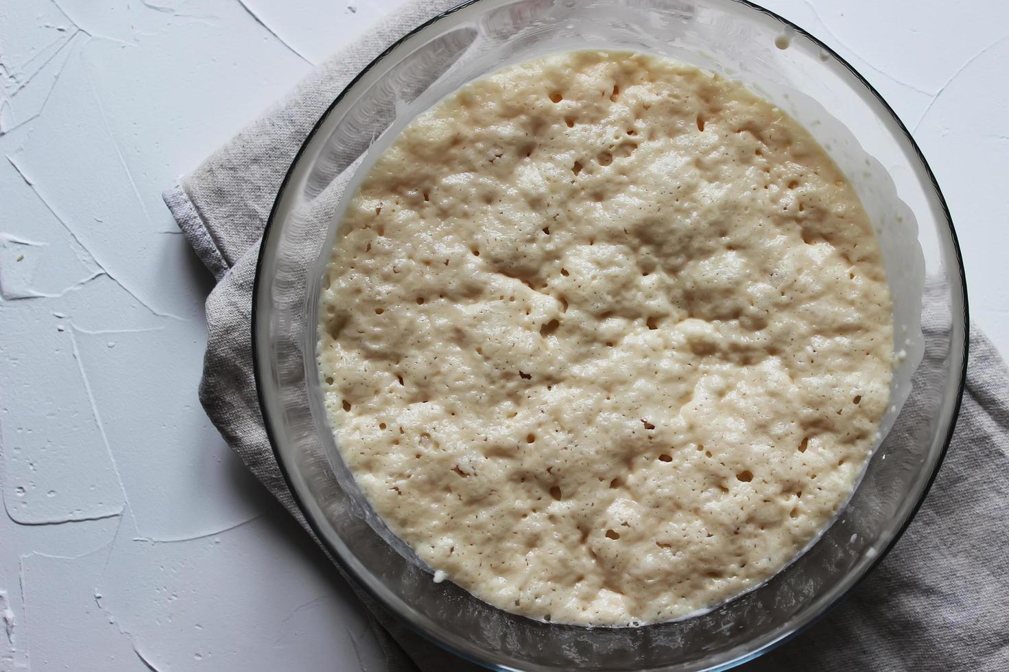 Yeast dough in a large glass bowl. Homemade cake. Concept of homework during the quarantine period. photo