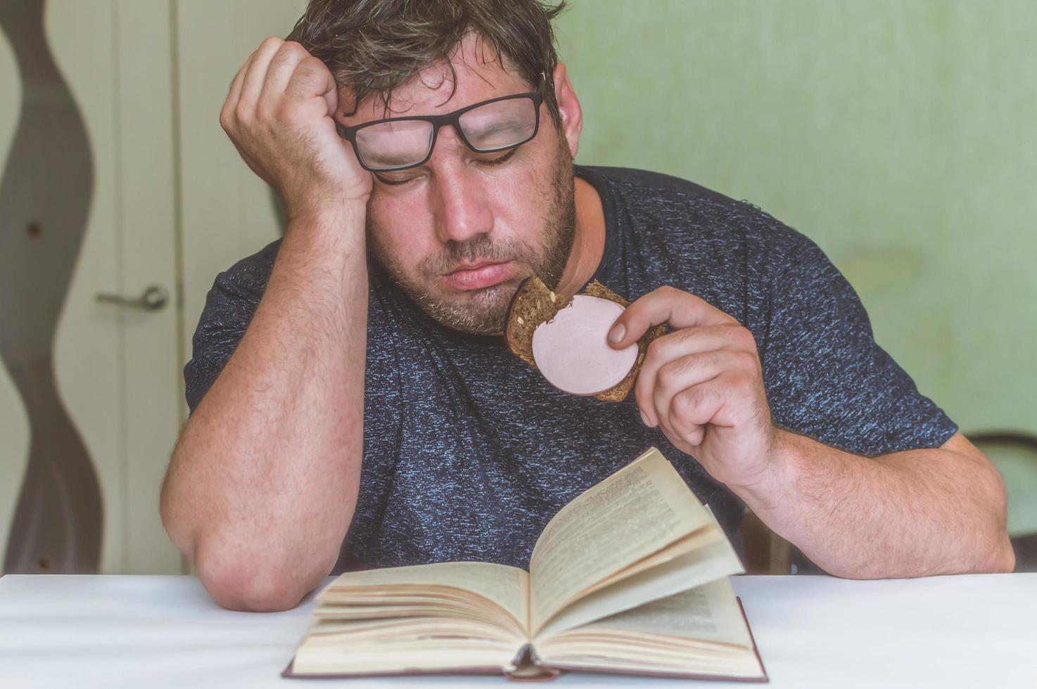man reading a book at the table, having a snack while reading, a short break photo