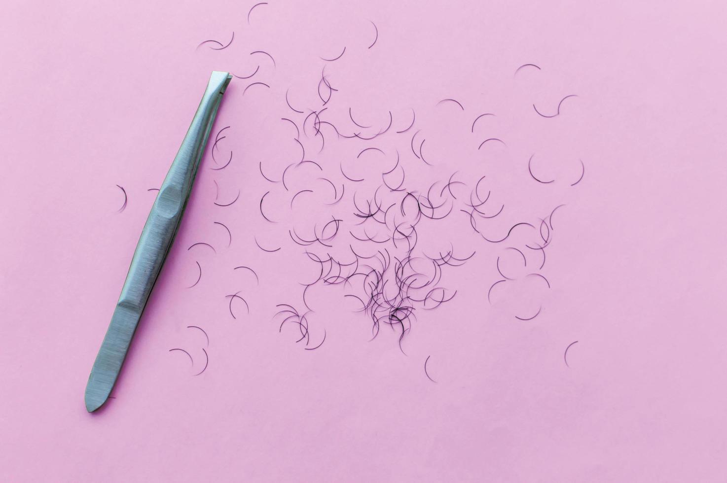 pinzas para depilarse las cejas y el cabello sobre un fondo rosa con lugar para escribir foto