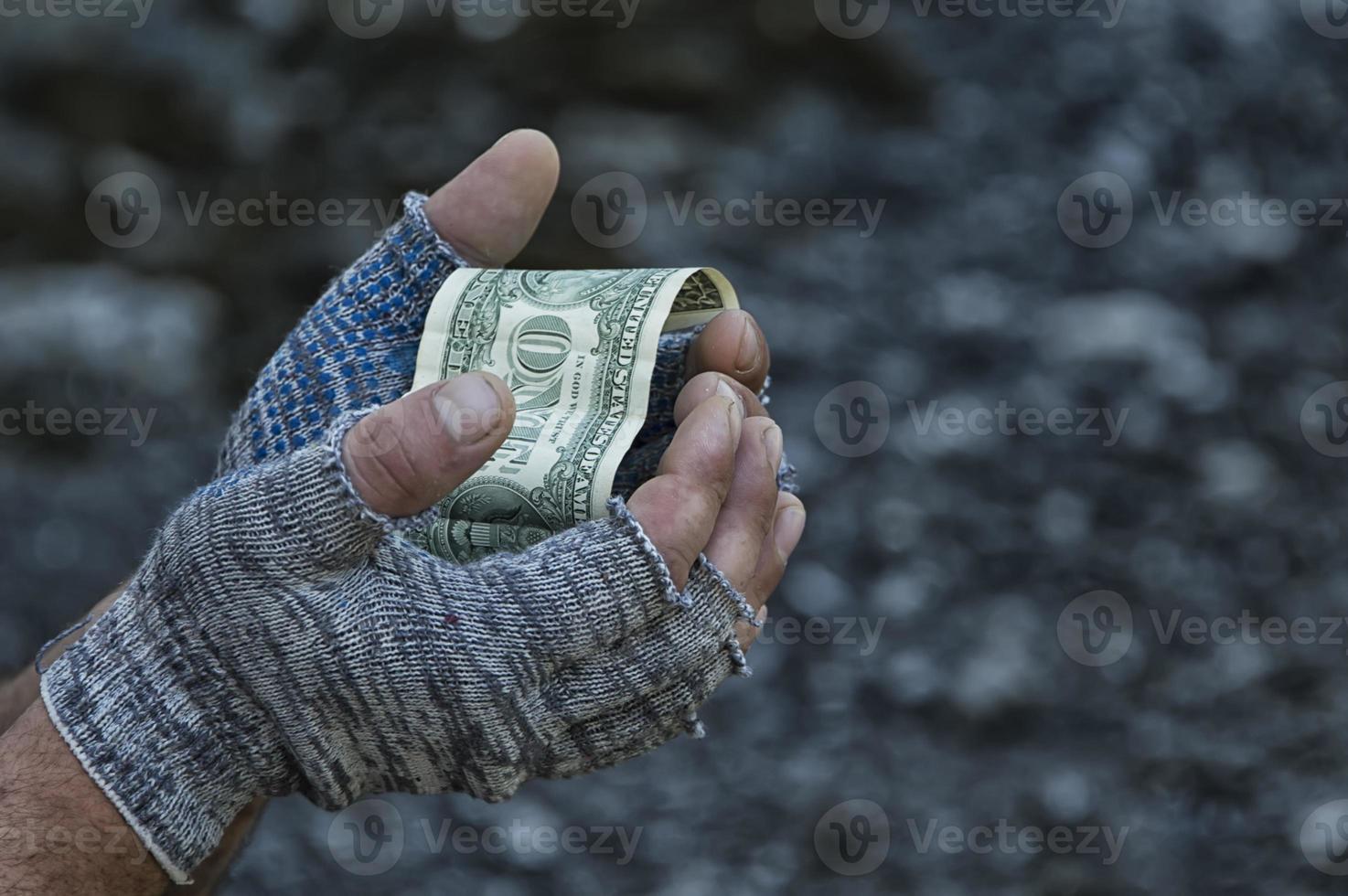 un dólar en manos de un vagabundo con guantes. pobreza, hambre, desempleo. foto