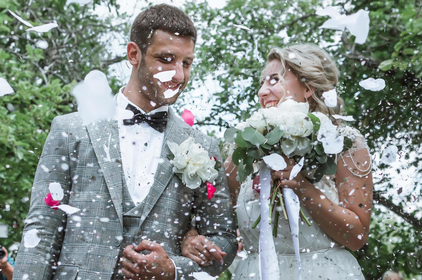 novios en la ceremonia de la boda. felicitaciones de los invitados. ducharse con pétalos de rosa. enfoque selectivo. grano de la película. foto