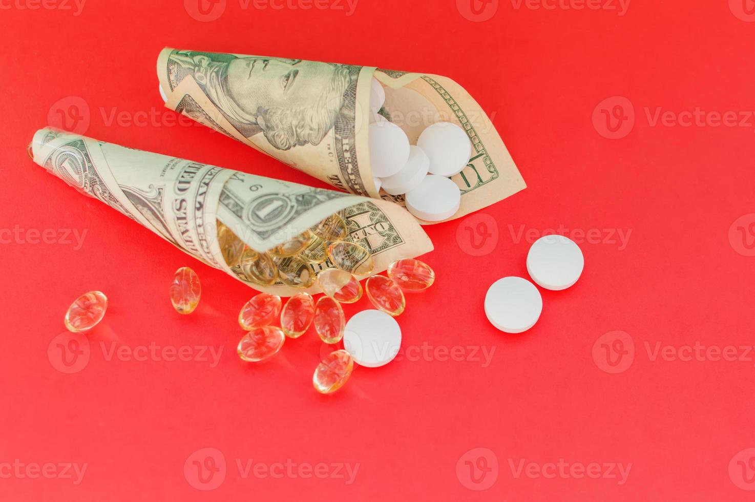 Medicines, vitamins and antioxidant supplements wrapped in money on a red background. The concept of expensive treatment. photo