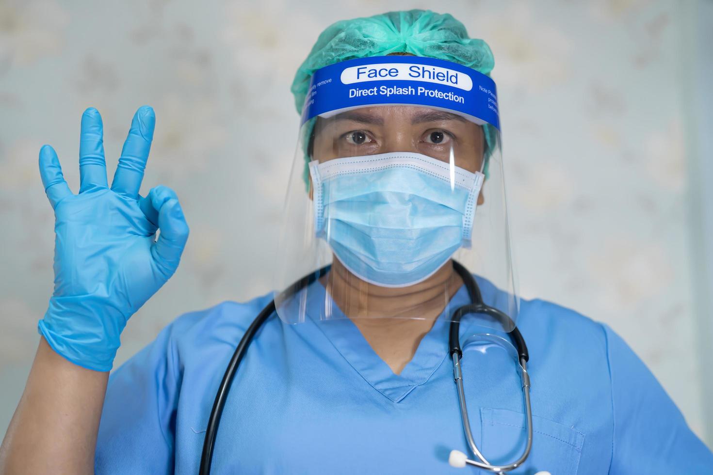 Asian doctor wearing face shield and PPE suit new normal to check patient protect safety infection Covid-19 Coronavirus outbreak at quarantine nursing hospital ward. photo